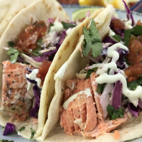 How to cook simple salmon tacos that are topped with slaw, spicy cream sauce and salsa. A healthy meal for under 500 calories per serving that provides 29 grams of protein, 4 grams of fiber, 15% of the daily value for potassium and omega-3 fatty acids.