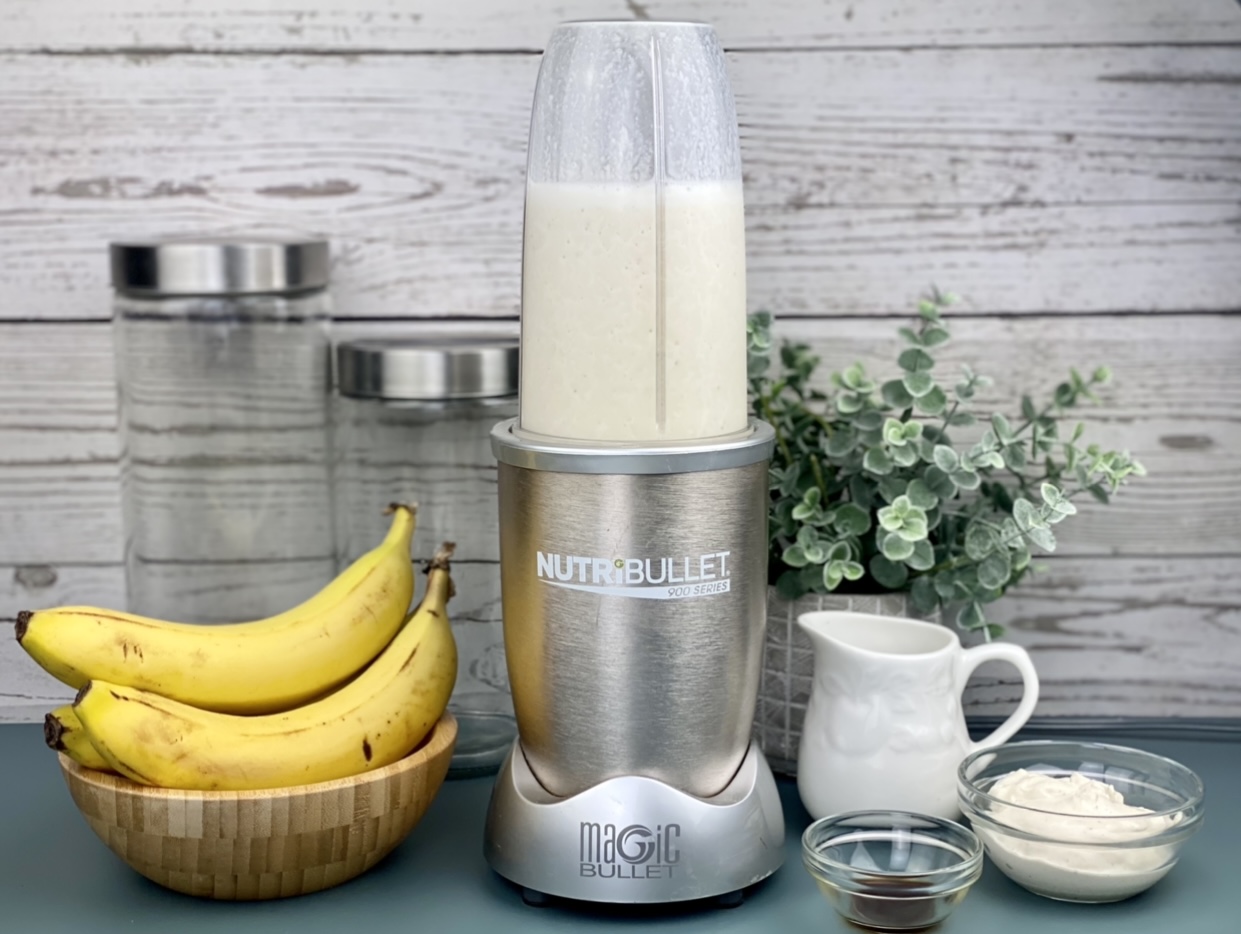 Picture of a the ingrediets needed to make a banana protein smoothie. Shows banana, vanilla extract, milk, Greek yogurt and the blender. 