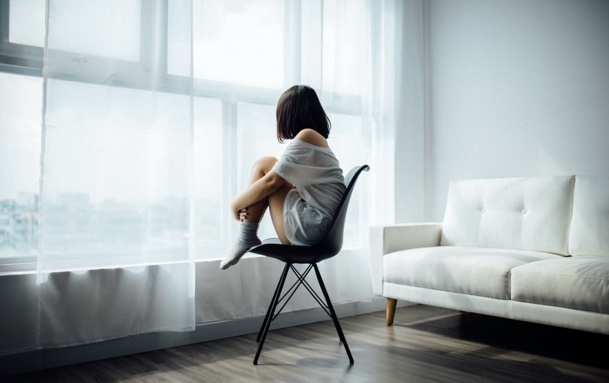 Girl sitting by a window, all alone highlighting the depression that can occur with disordered eating